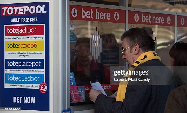 Racegoers place bets at Cheltenham Racecourse on the first day of the Cheltenham Festival on March 10, 2015 in Cheltenham, England. Thousands of...