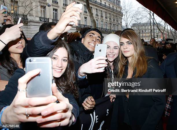 Cara Delevingne poses for photographs with fans as she attends the Yves Saint Laurent Beauty event at Galeries Lafayette on March 10, 2015 in Paris,...