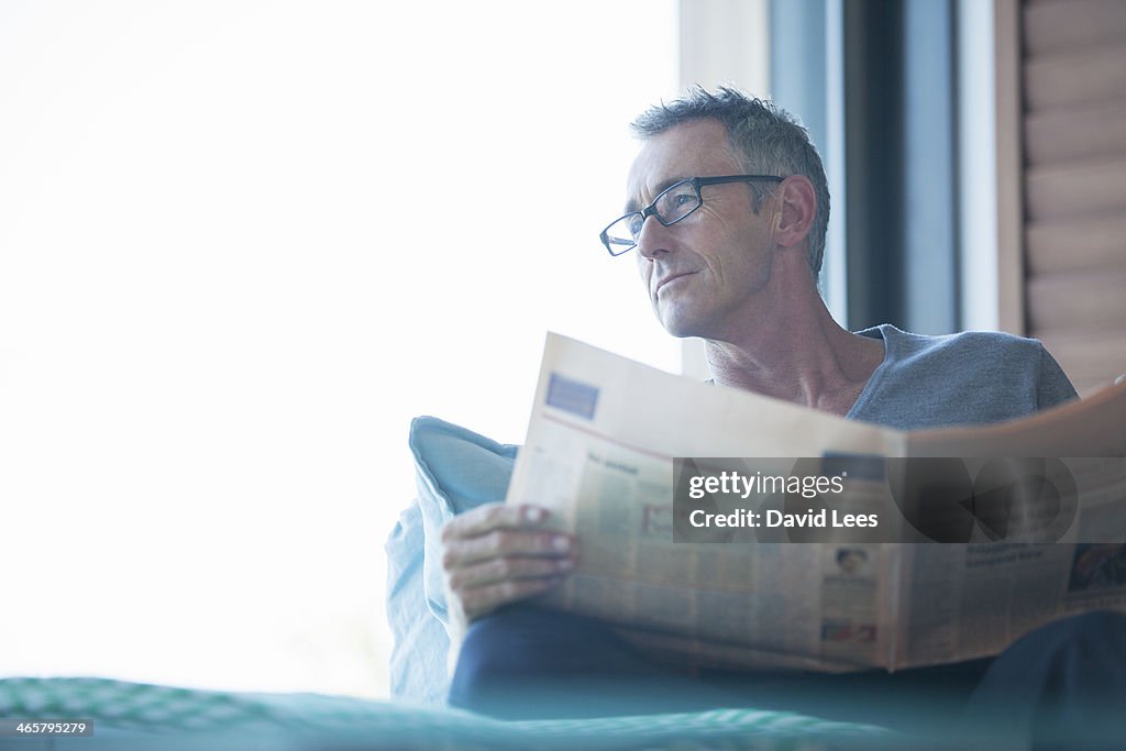 Close up of man reading newspaper in living room