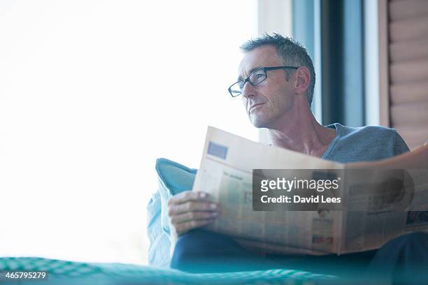 close up of man reading newspaper in living room - reading paper stock pictures, royalty-free photos & images