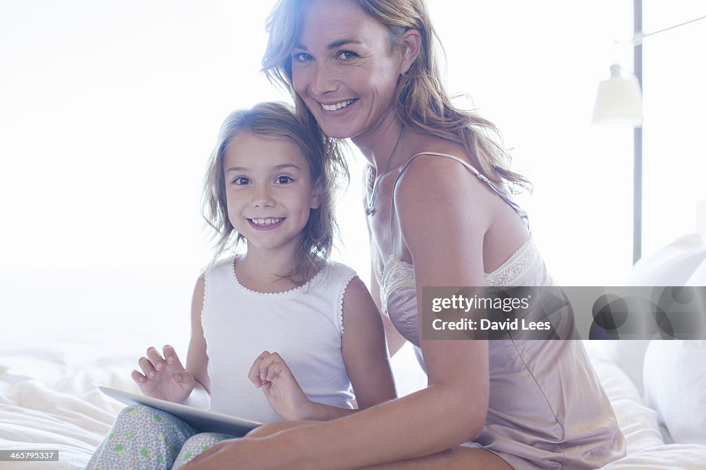Mother and daughter on bed using digital tablet