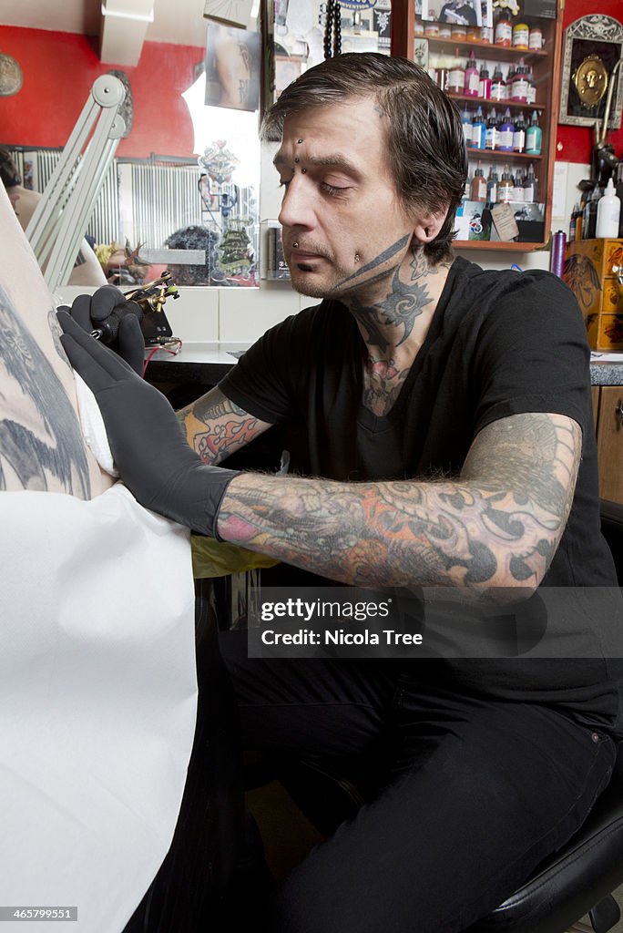 Tattoo artist doing a tattoo.