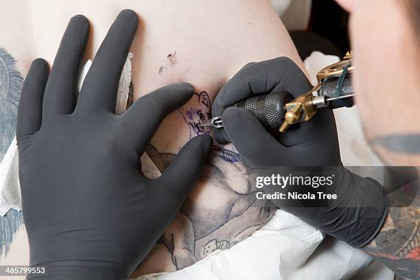 a tattoo artist doing a tattoo on someones back - tatoos stock pictures, royalty-free photos & images