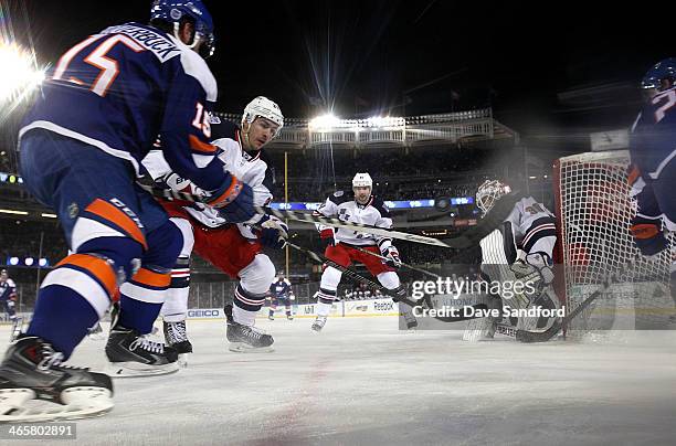 Ryan McDonagh of the New York Rangers and Cal Clutterbuck of the New York Islanders vie for the puck to the right of the Islanders net during the...