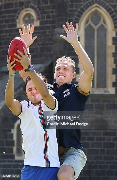 Formula One driver Felipe Massa marks a football against AFL player Joel Selwood at Melbourne Grammar on March 11, 2015 in Melbourne, Australia.