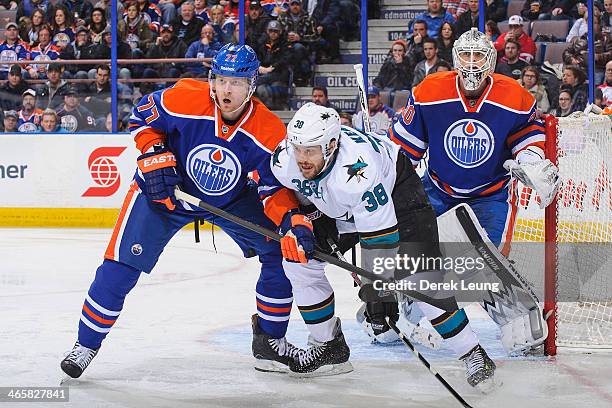 Boyd Gordon and Ben Scrivens of the Edmonton Oilers defend net against Bracken Kearns of the San Jose Sharks during an NHL game at Rexall Place on...