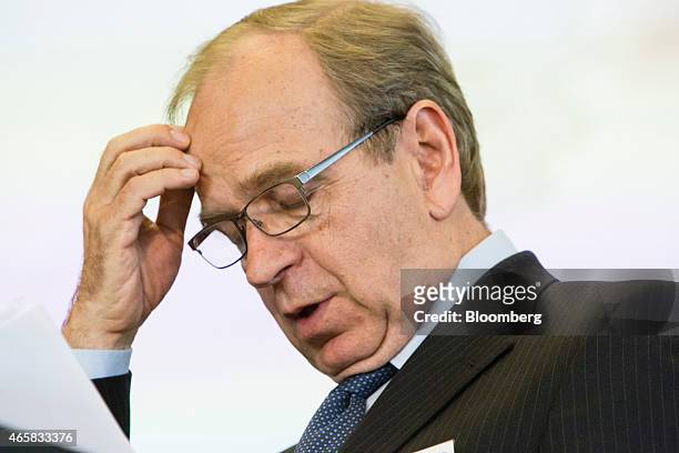 Erkki Liikanen, governor of the Bank of Finland, looks at documents as he addresses the European Central Bank and its watchers conference in...