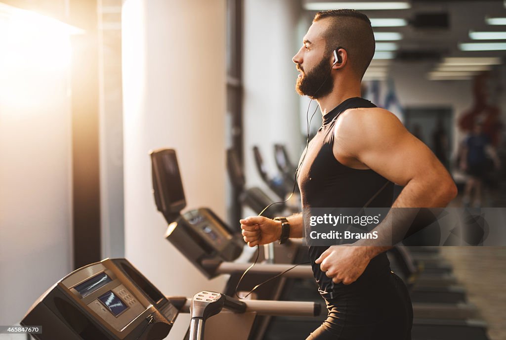 Side view of a young athlete running on treadmill.