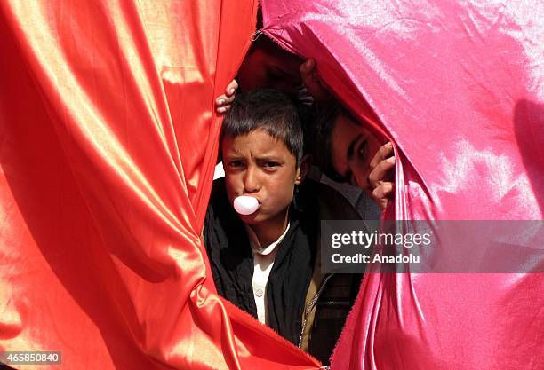 An internally displaced Afghan child blows bubble gum as the children prepare to attend a graduation ceremony organized by the Mobile Mini Circus for...