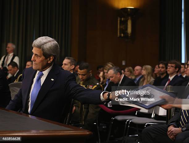 Secretary of State John Kerry hands off his papers before testifing before the Senate Foreign Relations Committee on Capitol Hill, March 11, 2015 in...