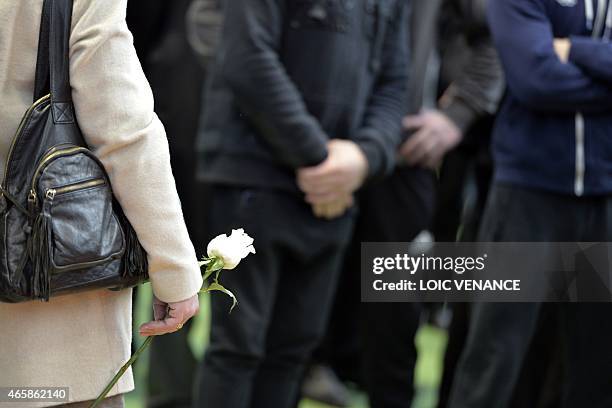 Woman holds a rose on March 11, 2015 at the Insep national Sport Institute in Vincennes, outside Paris, during a ceremony in memory of Olympic...