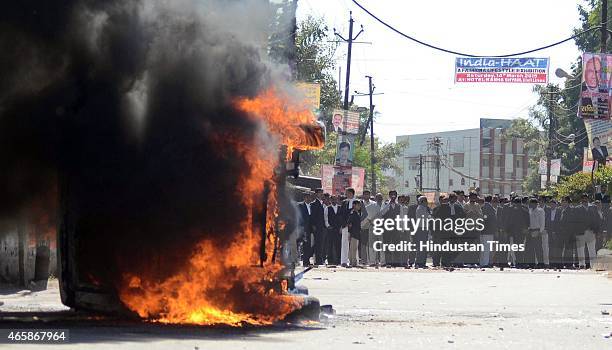 Policemen look on as vehicle set alight by angry lawyers outside the district court after a police inspector shot a lawyer in the court premises on...