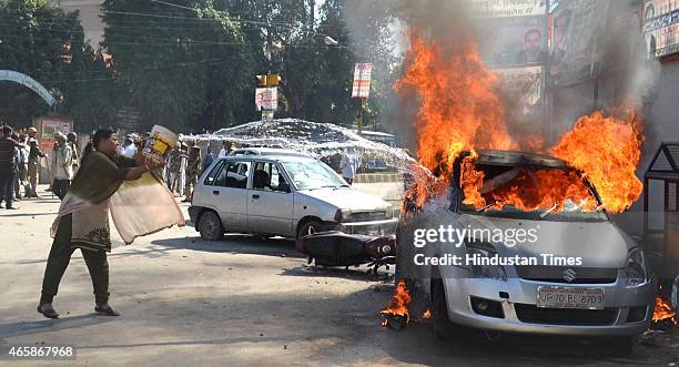 Woman trying to douse the car set aflame by angry lawyers outside the district court after a police inspector shot a lawyer in the court premises on...