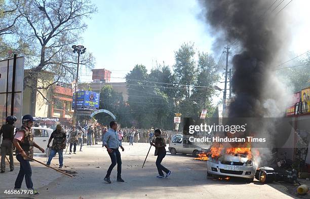 Policemen look as vehicle set alight by angry lawyers outside the district court after a police inspector shot a lawyer in the court premises on...