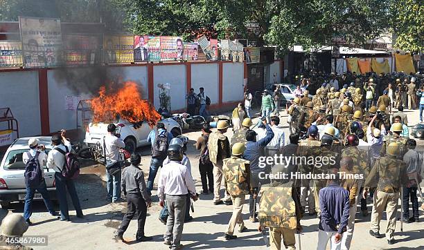 Policemen look as vehicle set alight by angry lawyers outside the district court after a police inspector shot a lawyer in the court premises on...