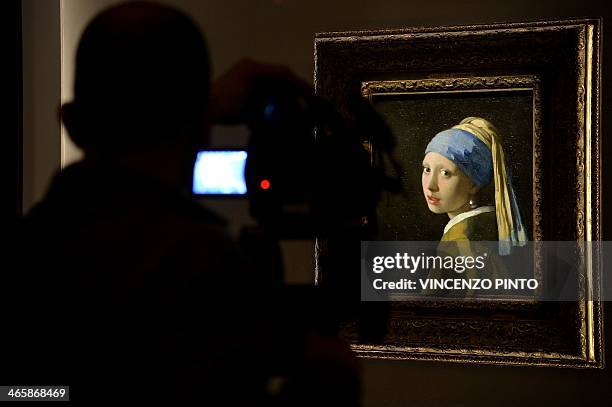 Man films the masterpiece "Girl with a Pearl Earring" by Dutch painter Johannes Vermeer during a preview of the exhibition "The Myth of the Golden...