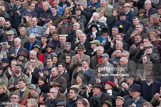 Racegoers await the arrival of the winner of the Betway Queen Mother Champion Steeple Chase in the paddock on the second day of the Cheltenham...