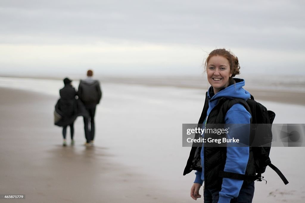 Young woman smiles on a wind swept beach