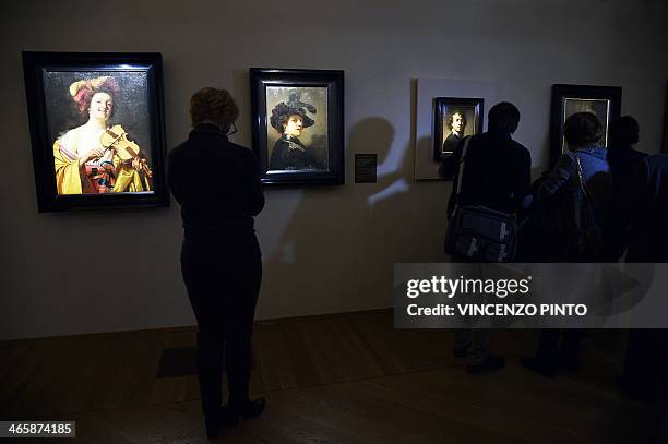 Visitors admire Gerrit van Honthorst's painting " Violin player " and Rembrandt's painting "Tronie of a Man with a Feathered Beret " during a preview...
