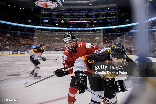 Defenceman Tim Bender of Germany is checked into the boards by forward Denis Malgin of Switzerland during the 2015 IIHF World Junior Championship on...