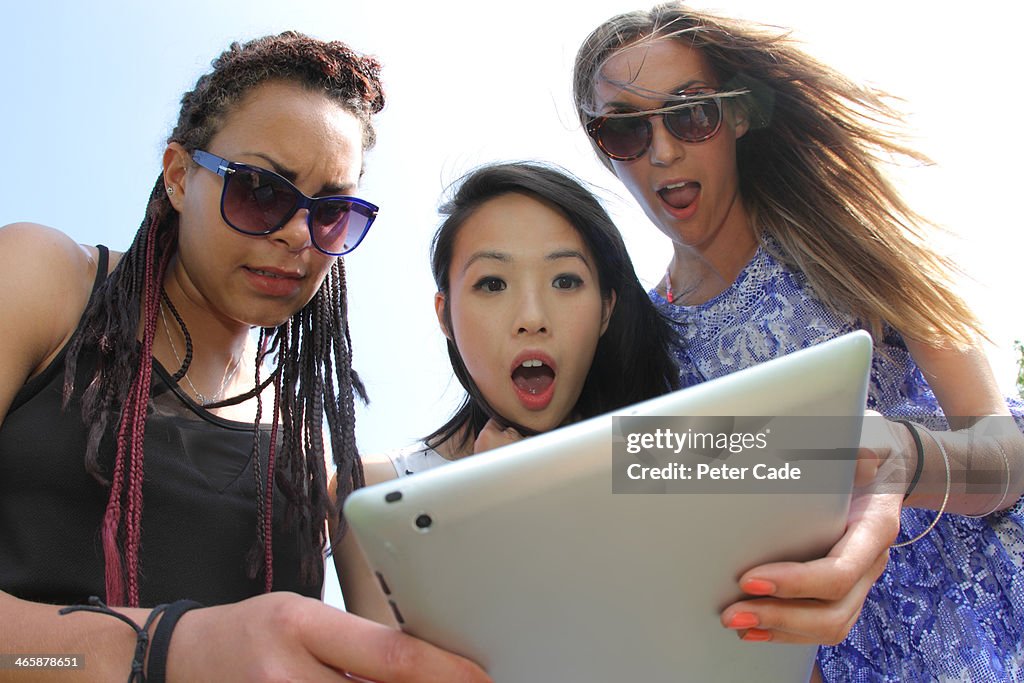 Three girls looking shocked at tablet