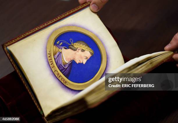Person holds a royal manuscript ordered by 16th century French king Francois 1er, depicting and describing the twelve Caesars, during the...