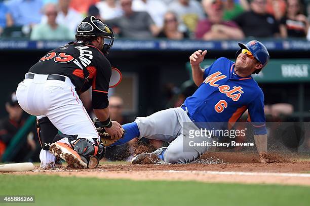 Matt den Dekker of the New York Mets is tagged out at home plate by Jarrod Saltalamacchia of the Miami Marlins during a spring training game at Roger...