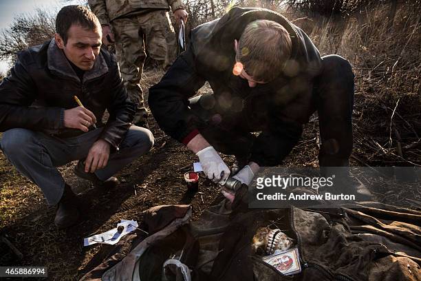 Police officers take the finger prints of a corpse found in a field on March 11, 2015 outside the village of Chornukyne, Ukraine. Pro-Russian rebels...