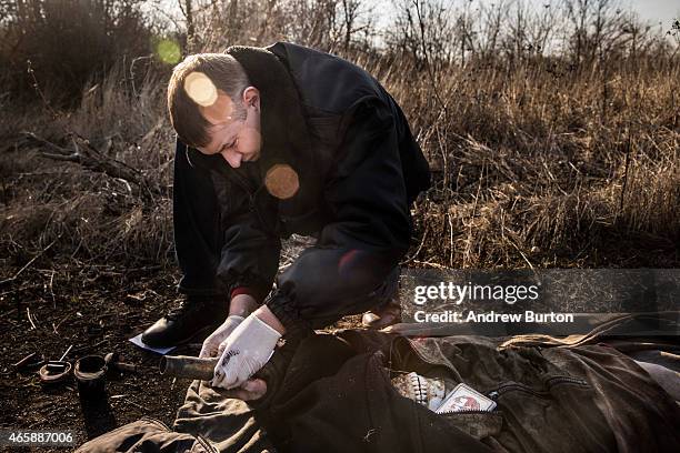 Police officers take the finger prints of a corpse found in a field on March 11, 2015 outside the village of Chornukyne, Ukraine. Pro-Russian rebels...