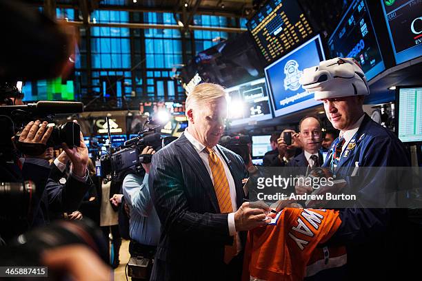 John Elway, executive VP of football operations of the Denver Broncos, signs a jersey on the floor of the New York Stock Exchange on the morning of...