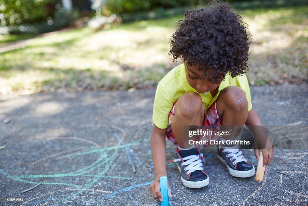 Boy drawing with chalk on sidewalk
