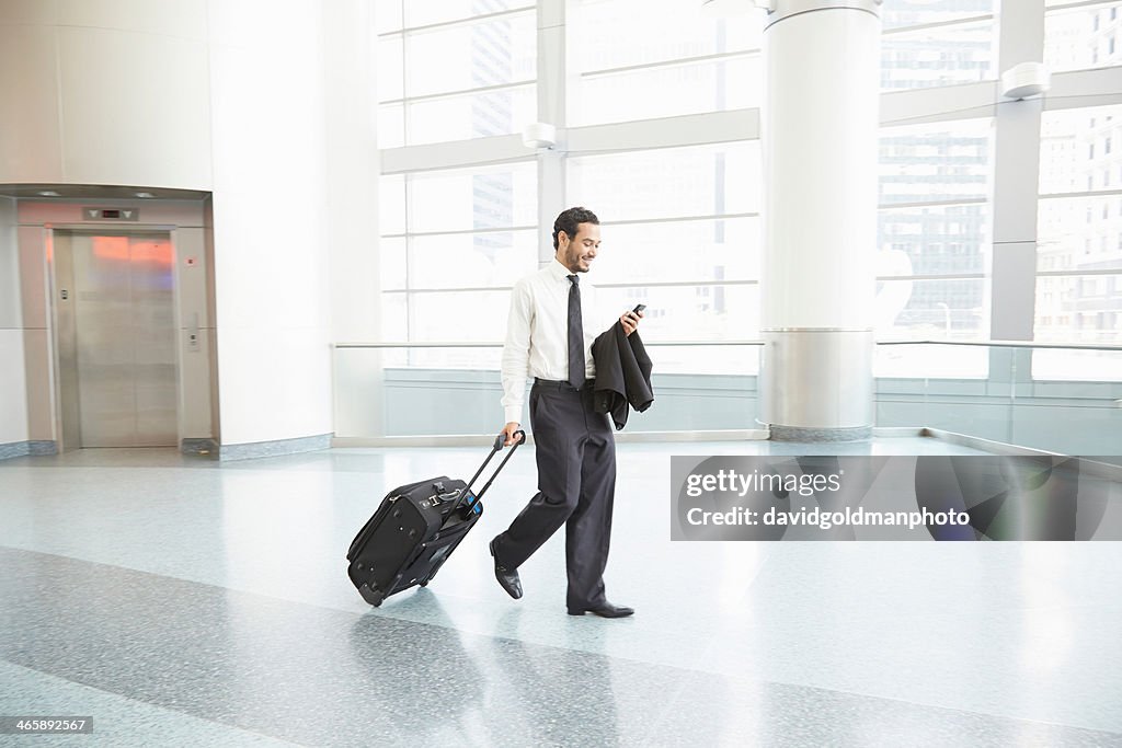 Businessman pulling wheeled suitcase