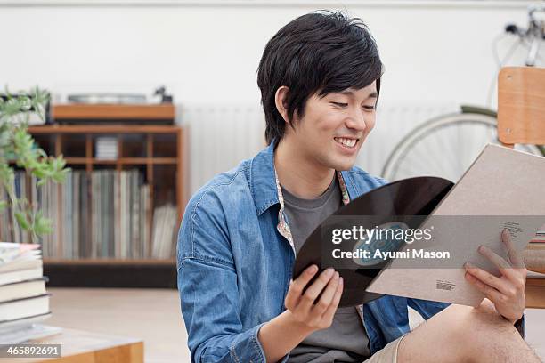 portrait of young man holding vinyl record - books collection stock-fotos und bilder