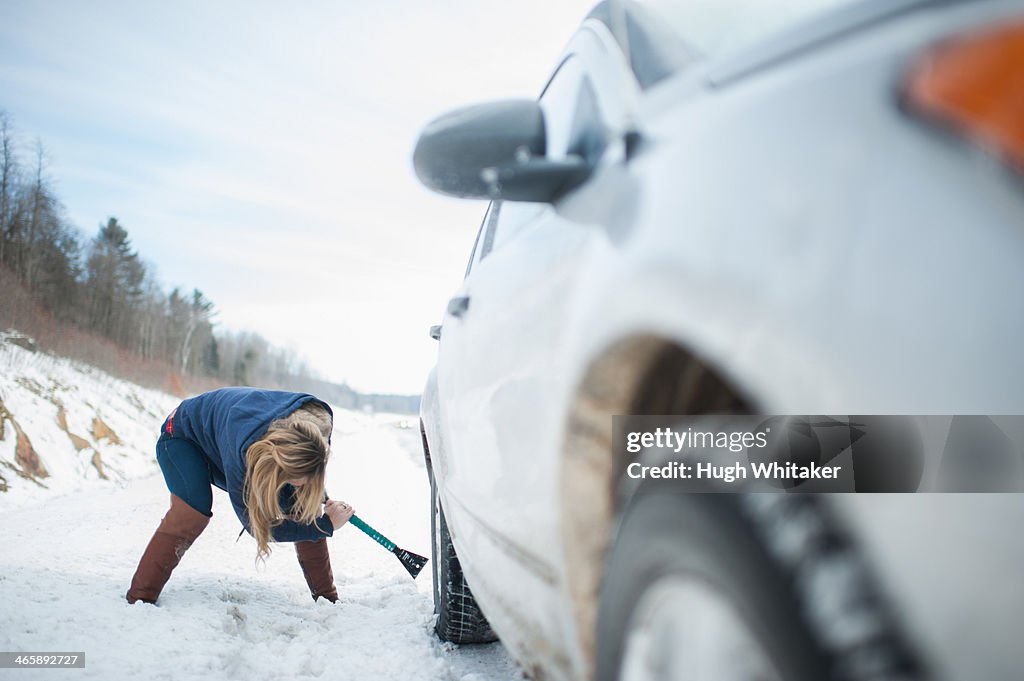 Woman digging car out from snow