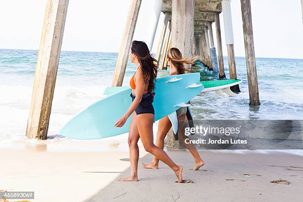 female friends on beach with surf boards, hermosa beach, california, usa - hermosa beach stockfoto's en -beelden