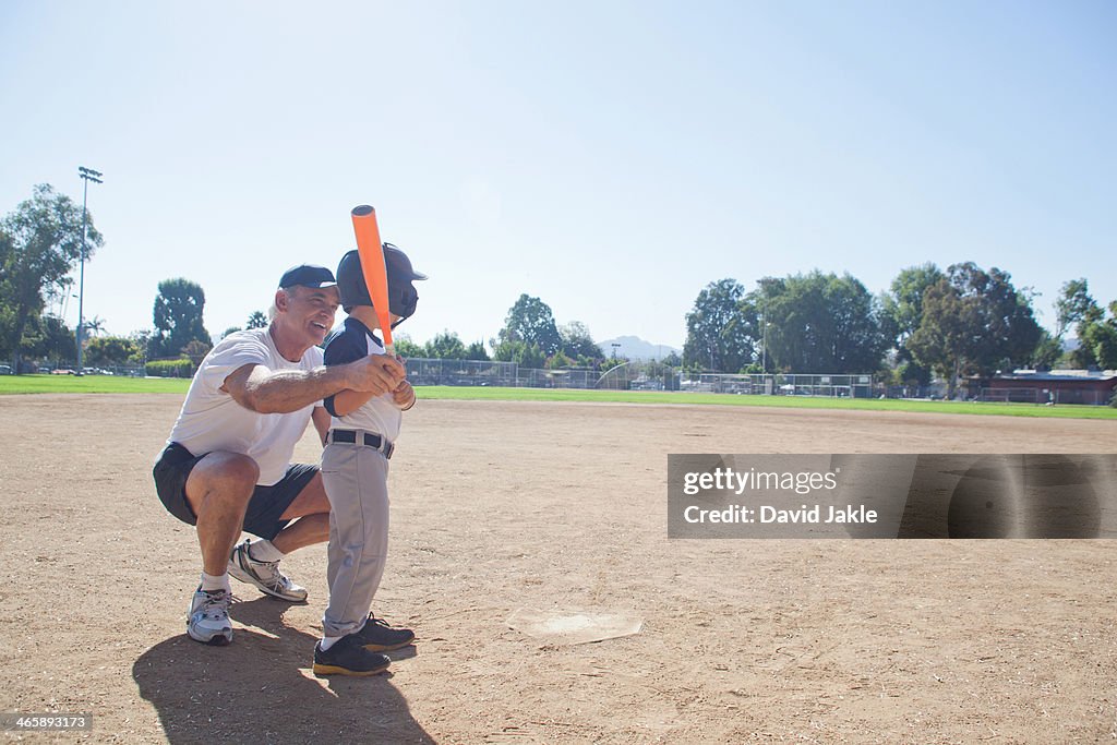 Man teaching grandson to play baseball