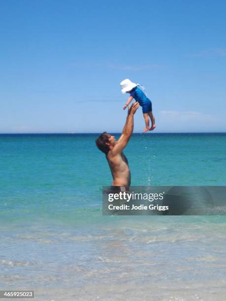 Father throwing child into the air whilst playing at the beach