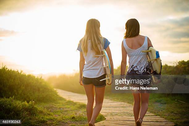 rear view of two friends walking with surf boards - banbossy stock pictures, royalty-free photos & images