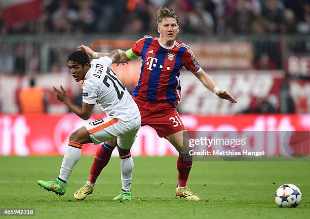 Douglas Costa of Donetsk and Bastian Schweinsteiger of Muenchen compete for the ball during the UEFA Champions League Round of 16 second leg match...