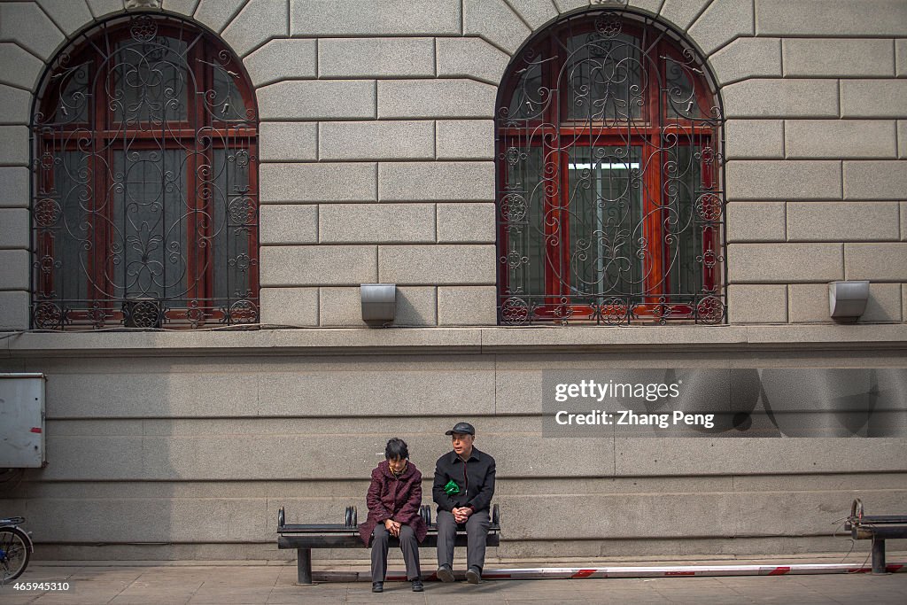 Two old people sits at roadside chatting.  China's pension...