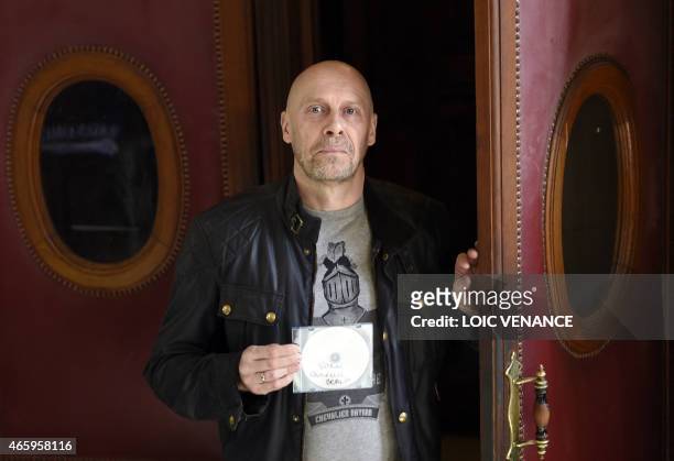 French far-right writer Alain Soral poses holding disc as he arrives at the Paris courthouse in Paris on March 12 for his trial for posting a picture...