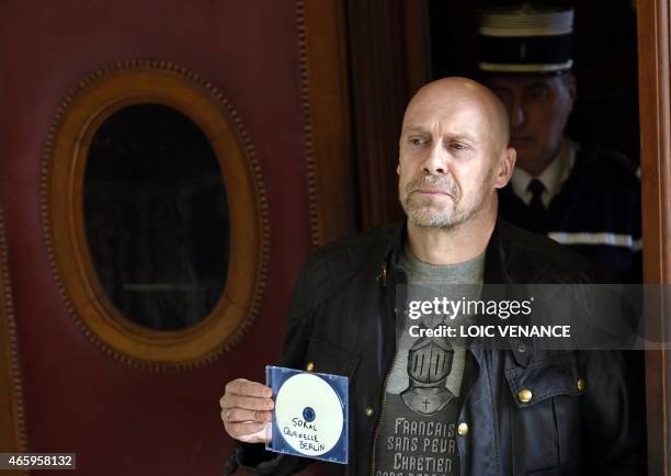French far-right writer Alain Soral poses holding disc as he arrives at the Paris courthouse in Paris on March 12 for his trial for posting a picture...