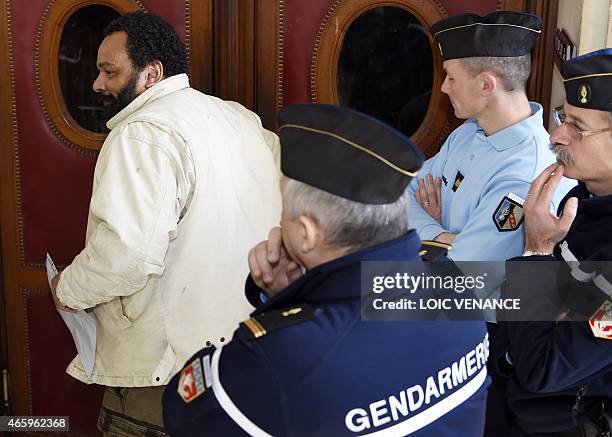 French controversial comic Dieudonne M'bala M'bala enters a courtroom in front of gendarmes at the Paris courthouse on March 12 for the trial of...