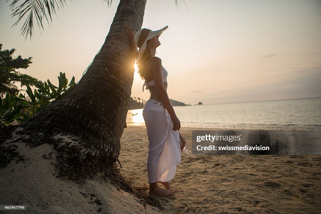 Young woman on tropical beach enjoying sunset