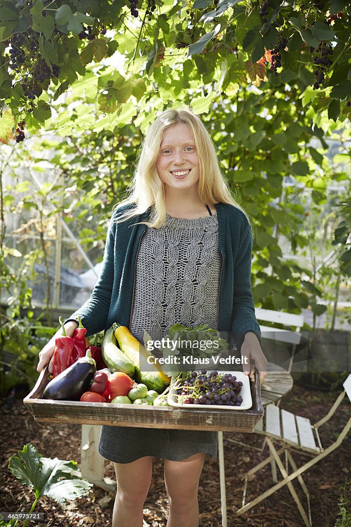 Young woman standing with tray of vegetables