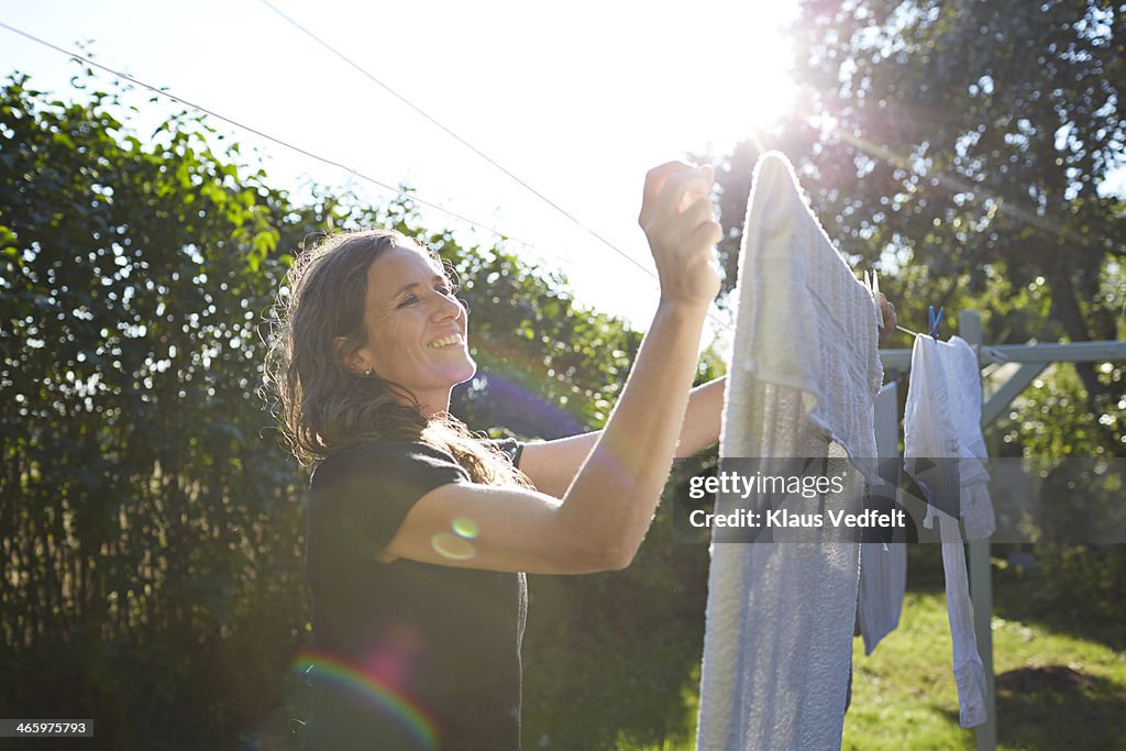 Woman hanging up laundry in her garden at sunset