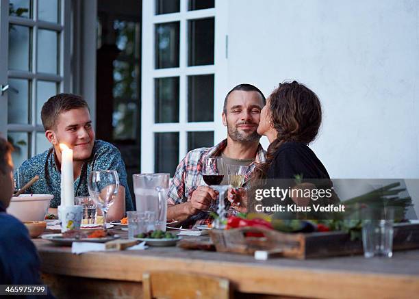 woman kissing husaband at outside dinner table - older woman younger man - fotografias e filmes do acervo