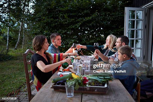 family toasting at outside dinner table - dinner jacket stock-fotos und bilder