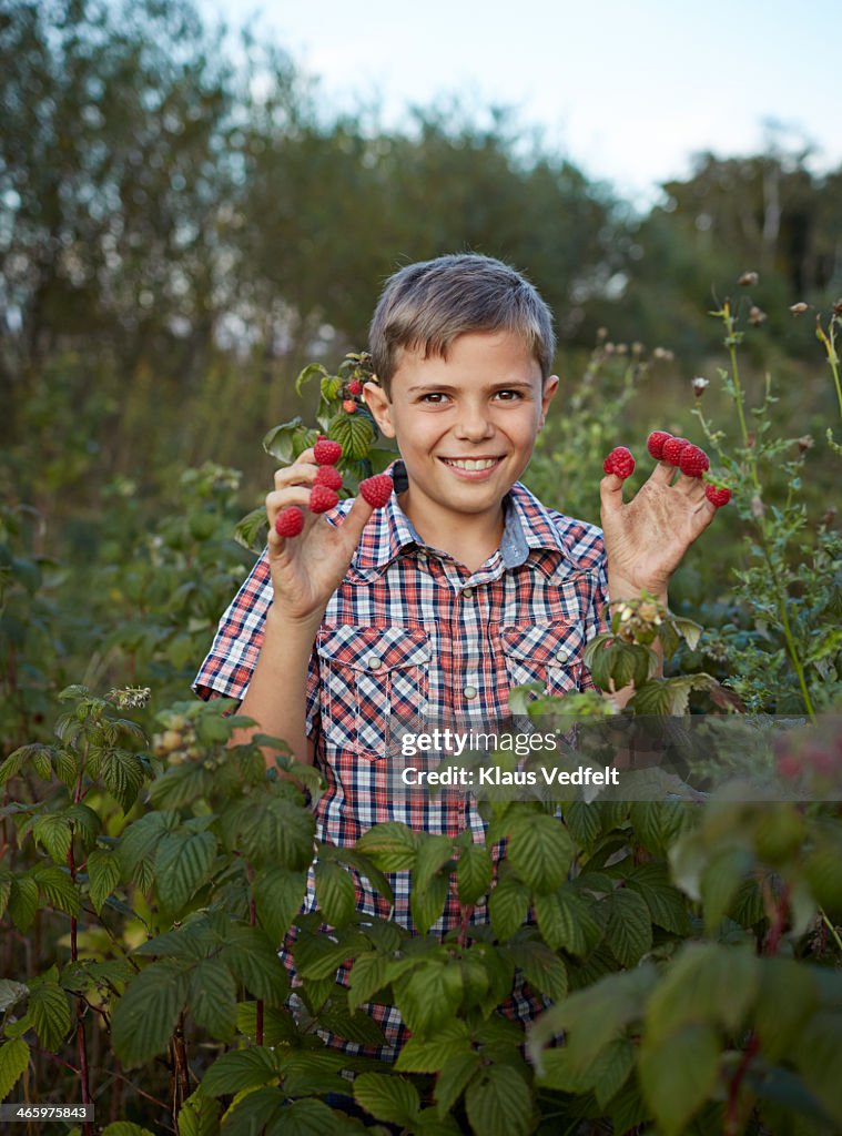 Happy boy with rasberries on each finger