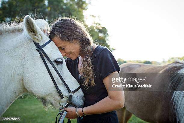 portrait of woman standing with her horse - animal behavior fotografías e imágenes de stock